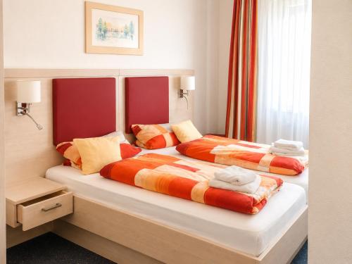 a bedroom with two beds with orange and yellow pillows at Hotel & Restaurant Möwchen in Norden