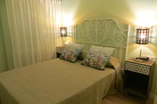 - une chambre avec un lit avec deux oreillers et deux lampes dans l'établissement Viv. Turística Museo del Comercio, à Salamanque