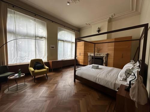 a bedroom with a canopy bed and a chair at Koeketiene Rooms in Ghent