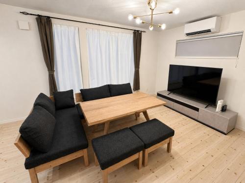 a living room with a couch and a table and a television at Akatsuki Villa 暁 in Asahikawa