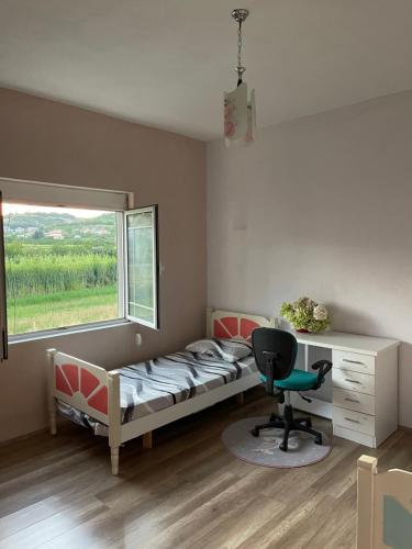 a bedroom with a bed and a desk and a window at Family-friendly in Pogradec