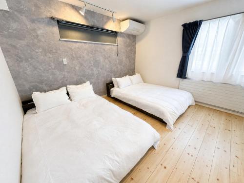 two beds in a room with white sheets at Akatsuki Villa 暁 in Asahikawa