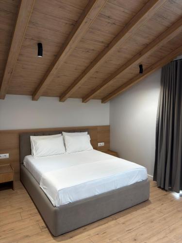 a bedroom with a large white bed with wooden ceilings at Airport Gate Hotel in Rinas