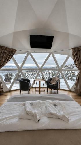 a bedroom with a bed with a tv and two chairs at Nawal Glamping - Domos in Trevelín