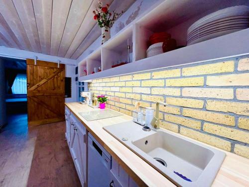a kitchen with a sink and a brick wall at VarázsLakos Birtok in Tázlár