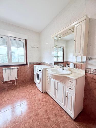 a bathroom with a sink and a washing machine at Casa Romai Portas in Romay