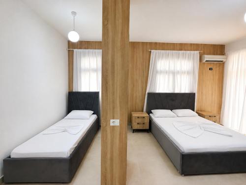 two beds in a room with two windows at Hotel Mjeshtri in Shëngjin