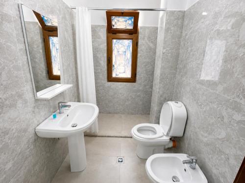 a bathroom with a sink and a toilet and a mirror at Hotel Mjeshtri in Shëngjin