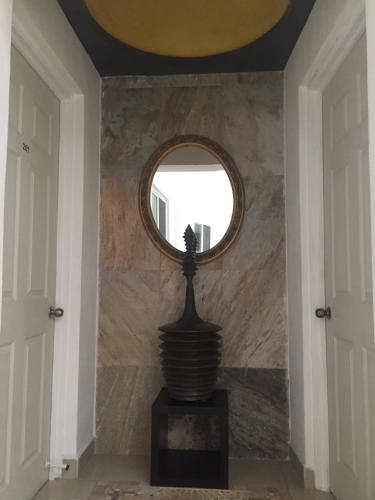 a round mirror on a wall with a vase in a hallway at Casa del Parque Vallarta in Puerto Vallarta