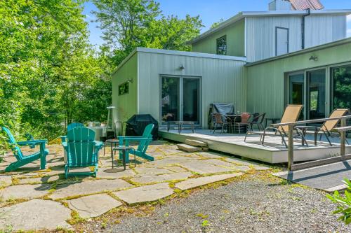 a patio with chairs and tables in front of a house at The Crag On the Acadia National Park Border - Deck, Fire Pit, Steps to Trails in Otter Creek