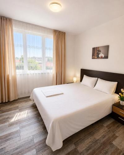 a large white bed in a room with windows at Alex City Apartment Gabrovo in Gabrovo