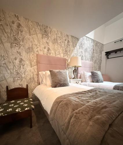 a bedroom with two beds and a wall with wallpaper at The Blue Bell Inn in Weaverthorpe