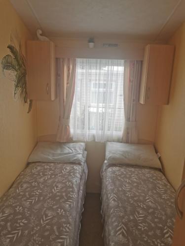 two beds in a small room with a window at Happy Days Seaside Trusthorpe in Trusthorpe