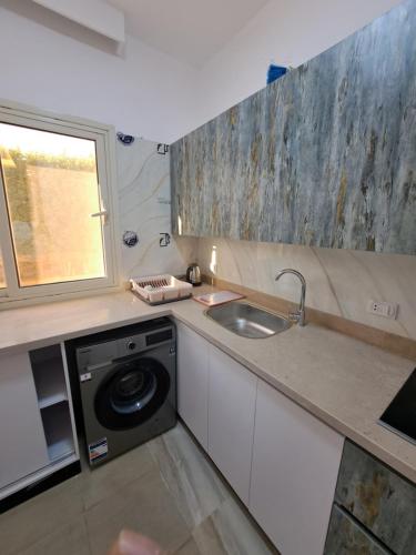 a kitchen with a sink and a washing machine at Adel Apartments at alkarma resorts& aquapark in Hurghada