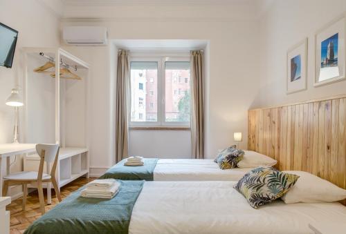 two beds in a room with a desk and a table at Home Out Rooms & Apartments in Lisbon