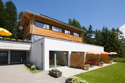 a house with a white facade and wood at Bed and Breakfast Raschainas Lenzerheide in Sporz