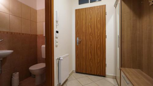 a bathroom with a toilet and a wooden door at Villa Palazzo Apartments in Siófok