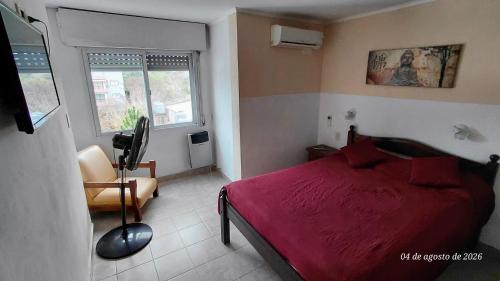 a bedroom with a red bed and a chair at Ayalata del Rio in Colón