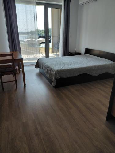 a bedroom with a bed and a chair and a window at Apartmany BlueWave Riverside Piešťany in Banka
