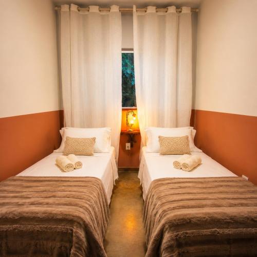 two beds in a small room with a window at Villa Pella - Chalé Tulipa- com café manhã in Brumadinho