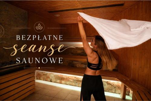 a woman standing in a sauna holding a blanket at Hotel Wellness & Spa Nowy Dwór in Rzeszów