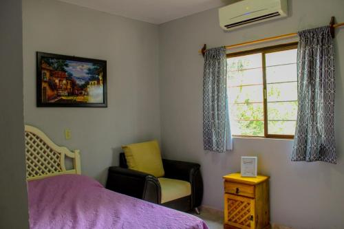 a bedroom with a bed and a chair and a window at Hotel Cielo Huasteco in Ciudad Valles