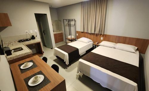a hotel room with two beds and a table at FLATS CERRADO santa casa in Montes Claros