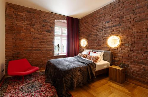 a bedroom with a brick wall and a bed and a red chair at Jannseni Premium Penthouse I Sauna I Free Parking in Pärnu