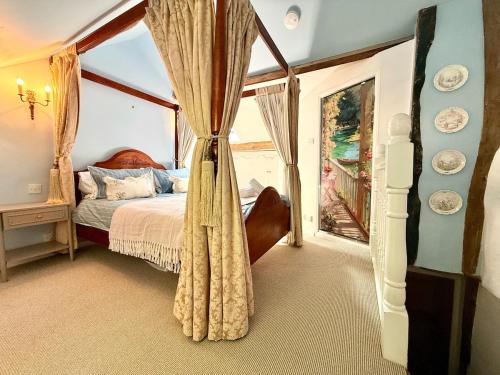 a bedroom with a canopy bed and a window at Wind in the Willows Moreton in Marsh in Moreton in Marsh
