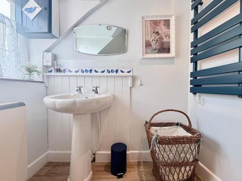 a bathroom with a sink and a mirror and a basket at Wind in the Willows Moreton in Marsh in Moreton in Marsh