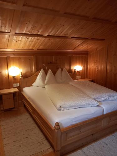 a bed in a wooden room with two lamps at Bad Kalkstein in Innervillgraten