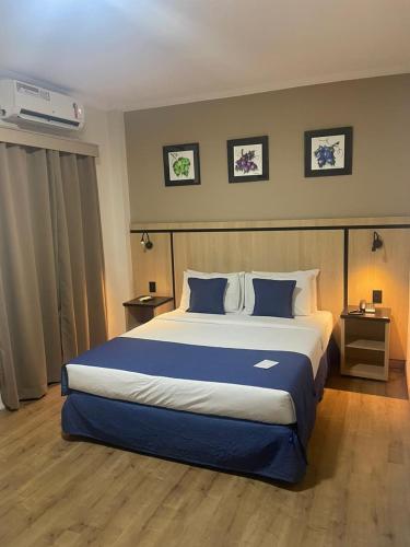 a bedroom with a large bed with blue pillows at Summit Suites Jundiai in Jundiaí