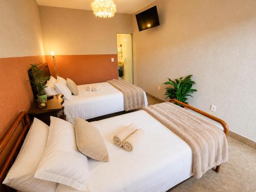 two beds in a hotel room with towels on them at Villa Pella - Chalé Cravo- café da manhã in Brumadinho