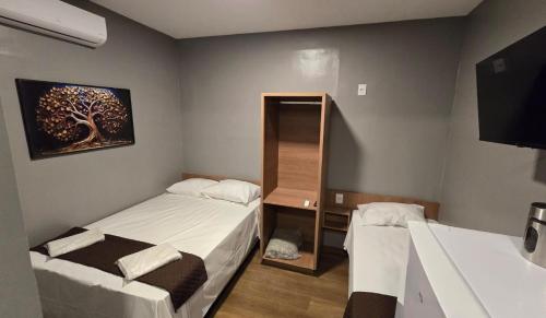 a small room with two beds and a tv at FLATS MELO unimontes in Montes Claros