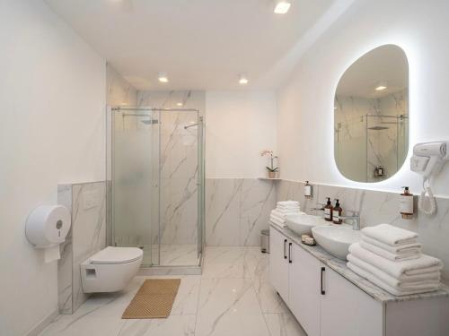 a bathroom with a shower and two sinks and a toilet at Maison Mark Luxury Suites & Spa in Belgrade