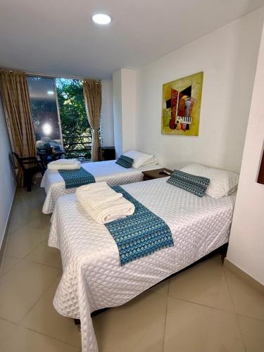 a room with three beds with towels on them at Living Montes in Medellín