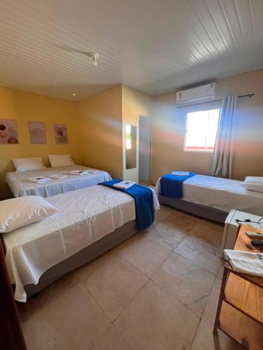 a bedroom with two beds and a window in it at Mini Suítes - Centro de Tutóia in Tutóia