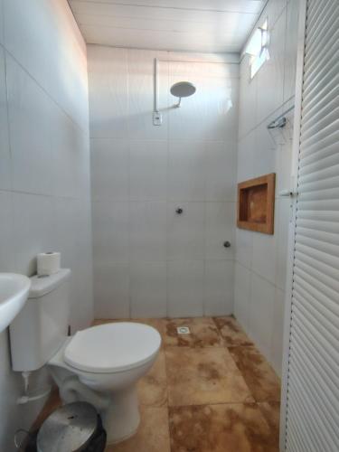 a white bathroom with a toilet and a shower at Mini Suítes - Centro de Tutóia in Tutóia