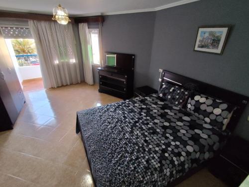 a bedroom with a bed and a dresser and a window at La Luna Rentals in Asilah