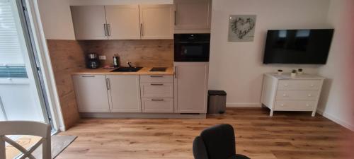 a small kitchen with white cabinets and a television at Ferienhaus Wellenklang in Glowe