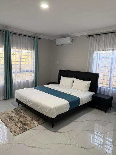 a bedroom with a large bed in a room with windows at Gabstel Apartments in Kitwe