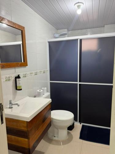 a bathroom with a toilet and a sink and a mirror at Hotel Guerra - Pousada Montebelo in Jaguaruna