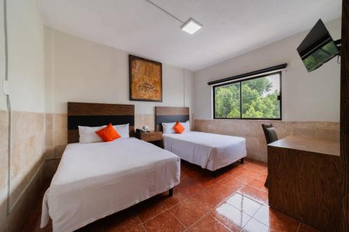 ein Hotelzimmer mit zwei Betten und einem Flachbildfernseher in der Unterkunft Nuve Express Abasolo in Torreón