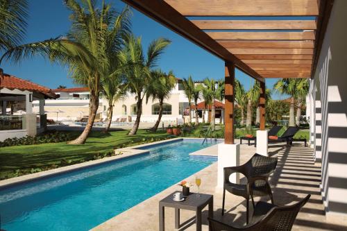 a view of the pool at a resort with a table and chairs at Dreams Dominicus La Romana Resort & Spa in Bayahibe
