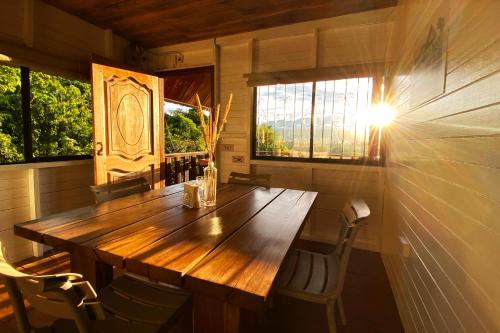 a wooden table in a room with chairs and windows at Coral Tree Lodge Tena in Tena