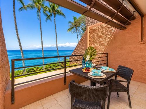 a balcony with a table and chairs and the ocean at Kuleana 613 1 Bdrm condo in Kahana