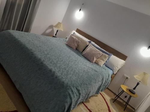 a bedroom with a bed with a blue blanket and two lamps at Casa Maria in Curtea de Argeş