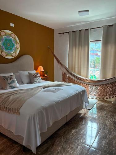 a bedroom with a large bed and a window at Trindade - Suíte Mandala in Trindade
