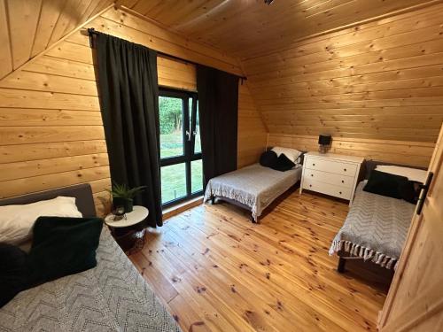 a bedroom with two beds in a log cabin at Stodoły na Mierzei in Kąty Rybackie
