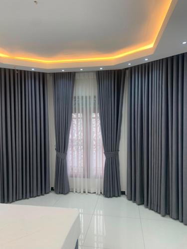 a room with gray curtains and a white table at Elysian Ridge Villa in Welimada